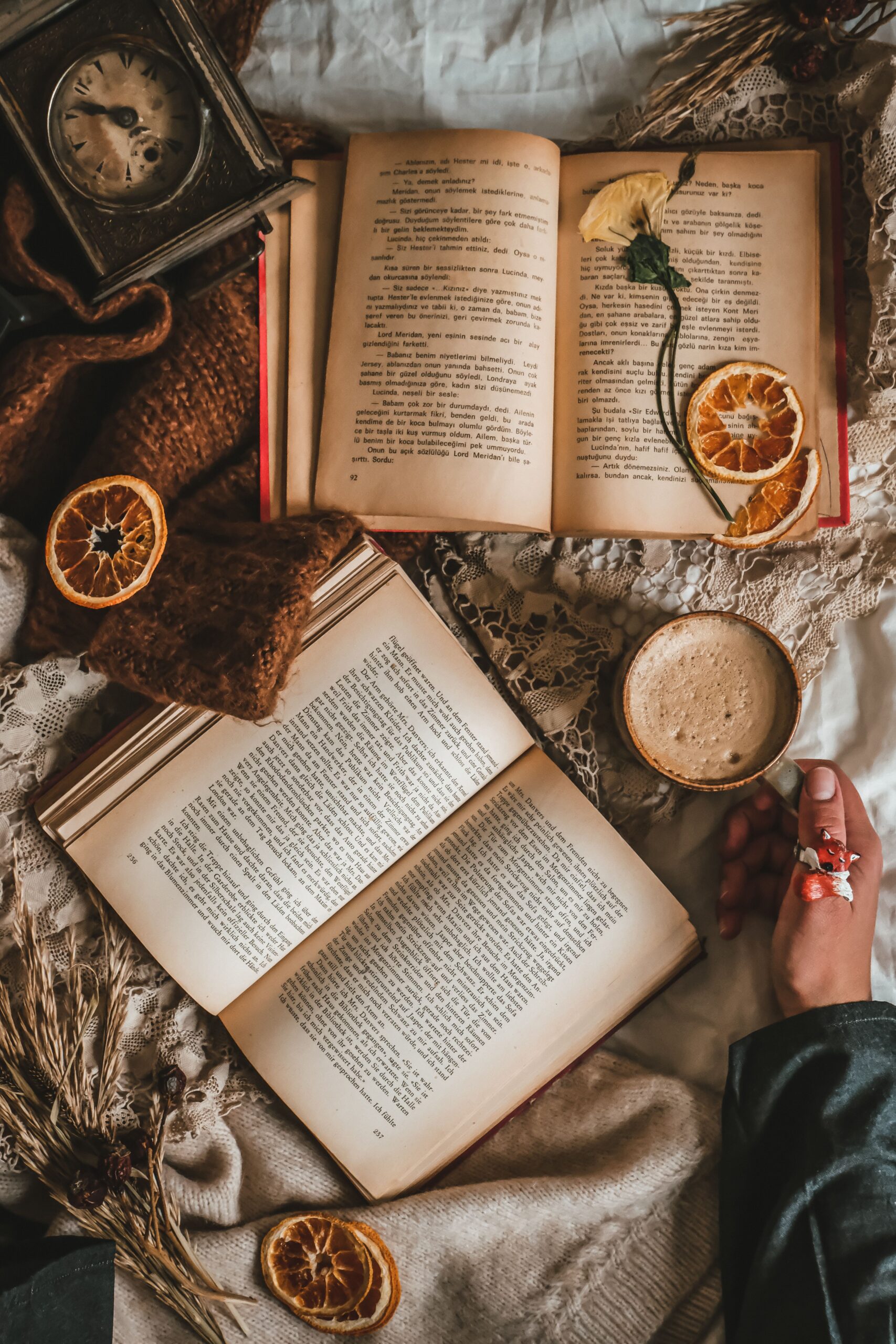 A cozy vintage flatlay featuring open books, dried oranges, and a cup of coffee, creating an autumnal vibe.